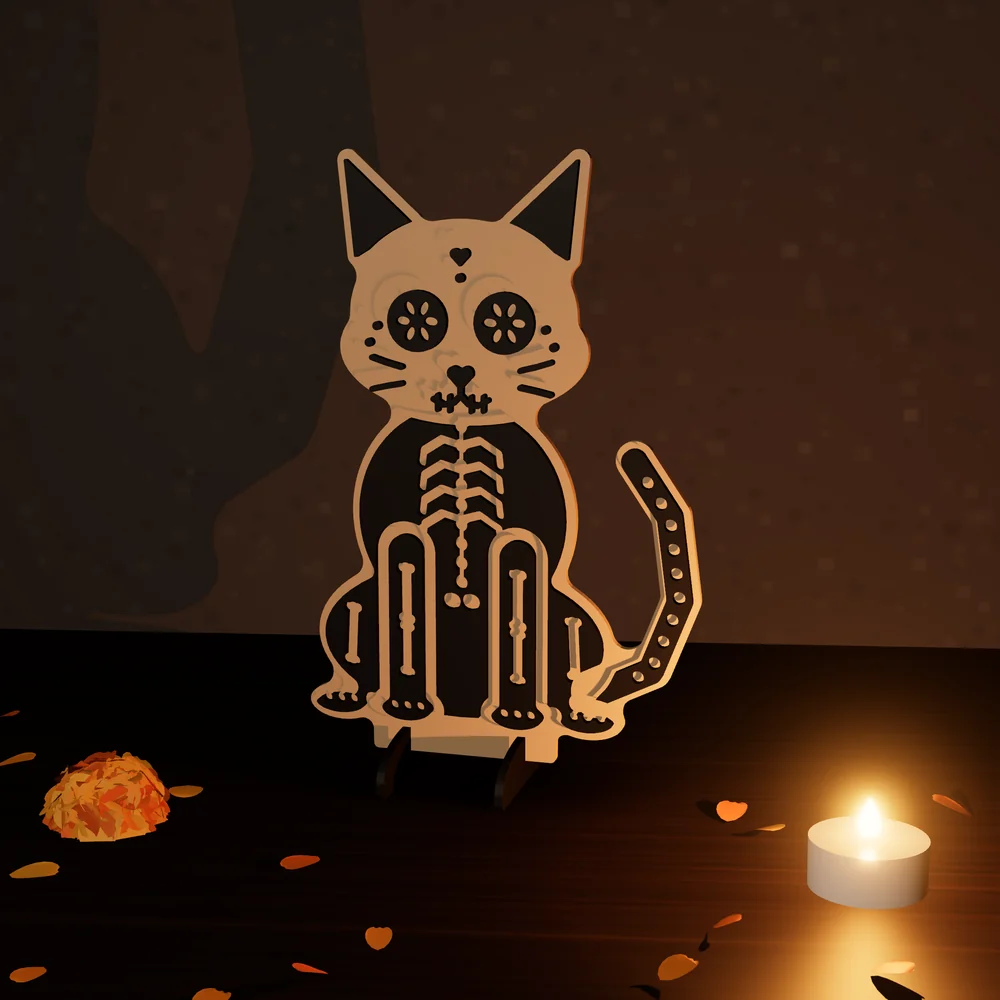 Gatito calavera en dos tonos: figura de MDF en 2 capas pintadas, parada en su base junto a una vela y pétalos de cempasúchil.